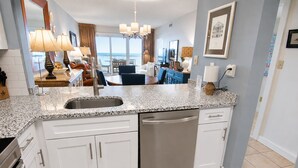A modern kitchen with a granite countertop, stainless steel appliances, and a view to the outside. - Land's End Resort - Oceanfront Views & Resort Amenities (Myrtle Beach)
