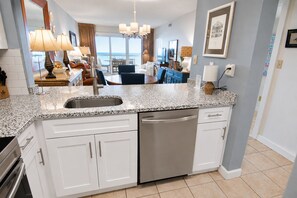 A modern kitchen with a granite countertop, stainless steel appliances, and a view to the outside. - Land's End Resort - Oceanfront Views & Resort Amenities (Myrtle Beach)