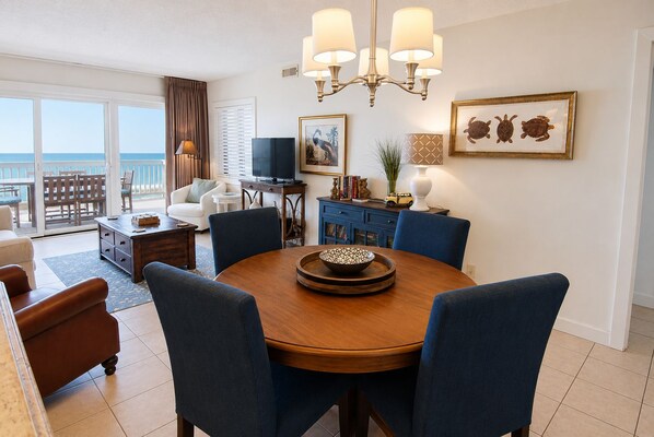 A dining area with a round table, chairs, and a chandelier. - Land's End Resort - Oceanfront Views & Resort Amenities (Myrtle Beach)