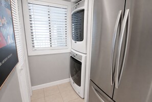 Eine kompakte Küche mit einem Edelstahl-Kühlschrank, einem eingebauten Backofen und einer Waschmaschine.