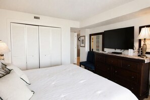 A hotel room with a bed, a dresser, a television, and a closet. - Land's End Resort - Oceanfront Views & Resort Amenities (Myrtle Beach)