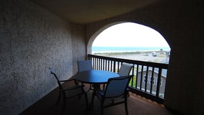 Ein Balkon mit Blick auf den Ozean, ein runder Tisch mit Stühlen und einem Geländer.