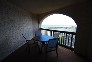 A balcony with a view of the ocean, a round table with chairs, and a railing. - Land's End Resort - Beachfront 2BR Escape with Ocean Views & Resort-Style Amenit (Myrtle Beach)
