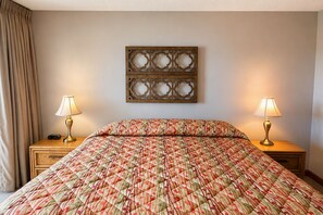 A hotel room with a bed, two bedside lamps, a wooden headboard, and a wall-mounted decorative panel. - Land's End Resort - Beachfront 2BR Escape with Ocean Views & Resort-Style Amenit (Myrtle Beach)