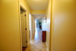 A hallway with doors, a plant, and a wooden bench. - Ocean View | King Suite, Balcony & Beach Access (Myrtle Beach)