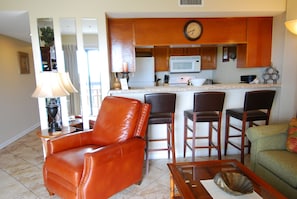 A living room with a leather chair, a green sofa, and a coffee table. - Ocean View | King Suite, Balcony & Beach Access (Myrtle Beach)