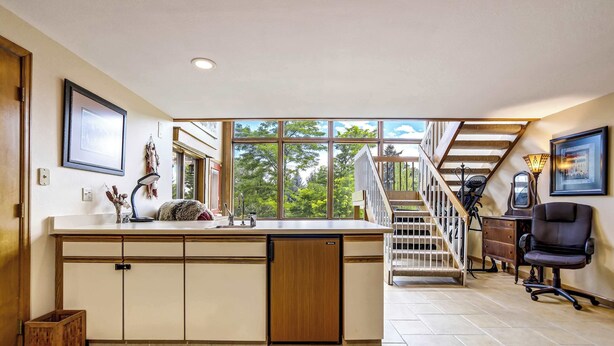 A spacious kitchen with a large island, a wooden staircase, and a view of greenery outside. - Garden Trails! Spacious Home by Garden of the Gods (Colorado Springs)