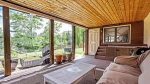 A covered patio with a wooden ceiling, a sofa, a table, and large windows offering a view of the outdoors. - Garden Trails! Spacious Home by Garden of the Gods (Colorado Springs)
