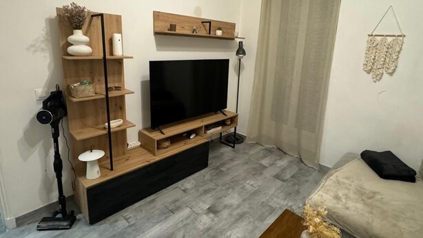 Un salon avec un téléviseur, des étagères en bois, un canapé et une table basse.