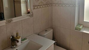 Une salle de bain avec un lavabo, des toilettes et un miroir.