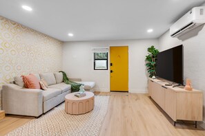 Ein modernes Wohnzimmer mit einer Couch, einem runden Couchtisch, einem Fernseher und einem Schrank.