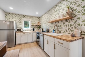 Eine moderne Küche mit weißen Schränken, einer Holz Arbeitsplatte und einer gefliesten Spritzschutzwand.