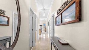 A hallway with a mirror, a bench, and a framed picture on the wall. - Seagrove Highlands Unit 1410 (Santa Rosa Beach)