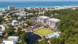 An aerial view of a coastal town with a large building complex, a swimming pool, and a bridge over a river. - Seagrove Highlands Unit 1410 (Santa Rosa Beach)
