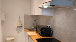A modern kitchen with a wooden countertop, stainless steel sink, and a built-in oven. - Studio with Garden at Villa Nemours (Chaville)