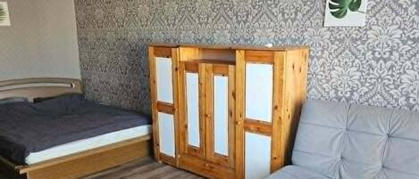A room with a bed, a sofa, a wooden table, and a patterned wall.