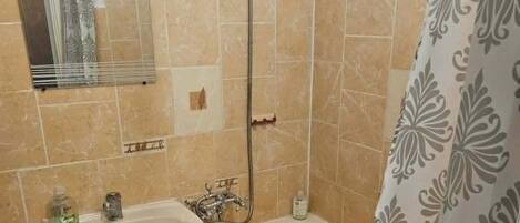 Et badeværelse med vask, spejl, brusebad og toilet.