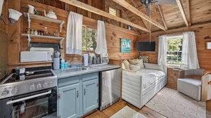 Una cabaña con cocina, comedor y zona de descanso.
