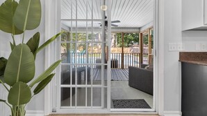 A sliding glass door leading to a patio with a pool, outdoor furniture, and a ceiling fan. - 5BR | Heated Pool, Hot Tub, Fire Pit & Backyard (Summerville)