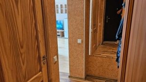 A wooden hallway with a door leading to a room, a tiled floor, and an arched doorway. - Serene 1-bedroom apartment in charming Liepāja perfect for relaxing (Liepāja)