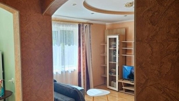 A living room with a sofa, a small round table, and a television. - Serene 1-bedroom apartment in charming Liepāja perfect for relaxing (Liepāja)