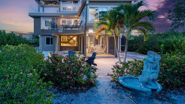 A two-story house with a balcony, outdoor seating, and a statue. - Widgeon Point (Fort Myers Beach)