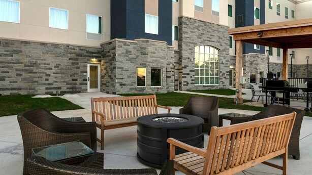A patio with wicker furniture, a fire pit, and a covered area with a grill.