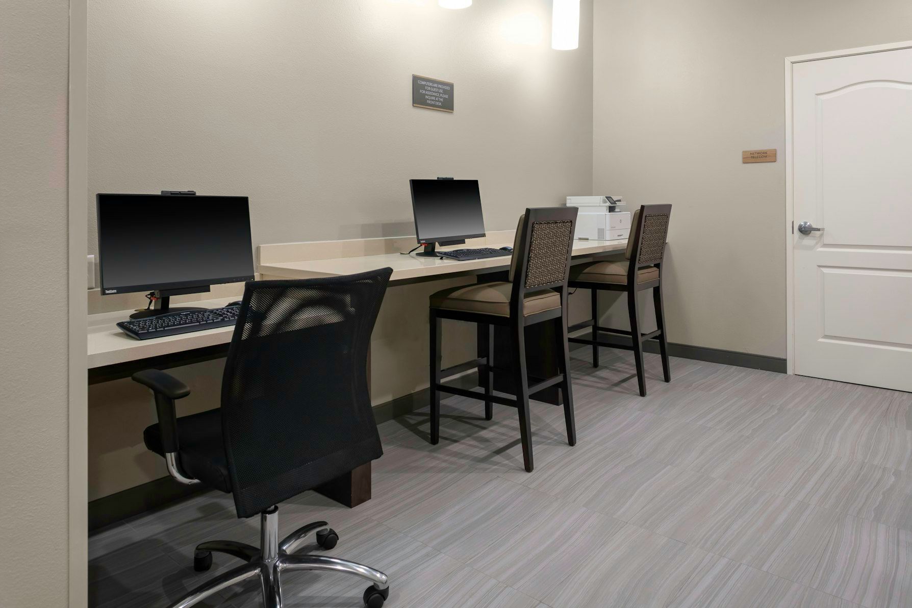 Une chambre d’hôtel équipée d’un bureau, d’un ordinateur, d’une chaise et d’une porte.