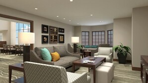 A hotel lobby with a sofa, armchairs, a coffee table, and a dining area.