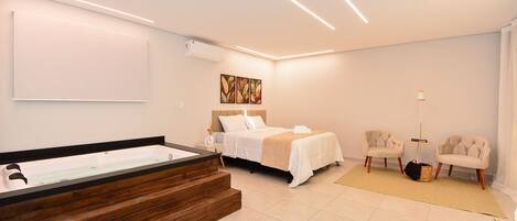A modern bedroom with a large bathtub, a bed, two armchairs, and a floor lamp.