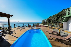 Ein Poolbereich mit Liegestühlen und Blick auf das Meer.
