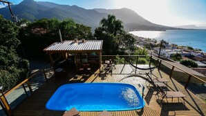 A wooden deck with a swimming pool, lounge chairs, and a small pavilion. - Casa com Piscina Vista Mar e Banheira (Palhoça)