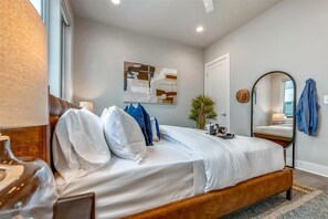 Ein Schlafzimmer mit Bett, Spiegel, Gemälde und Tür.