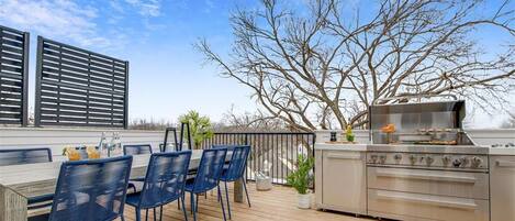 An outdoor deck with a dining area, a grill, and a potted plant.