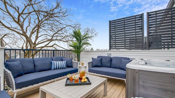 Un patio exterior con un sofá, una mesa de centro con bebidas y un jacuzzi.