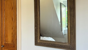 Ein Spiegel mit aufwendiger Rahmung an der Wand.