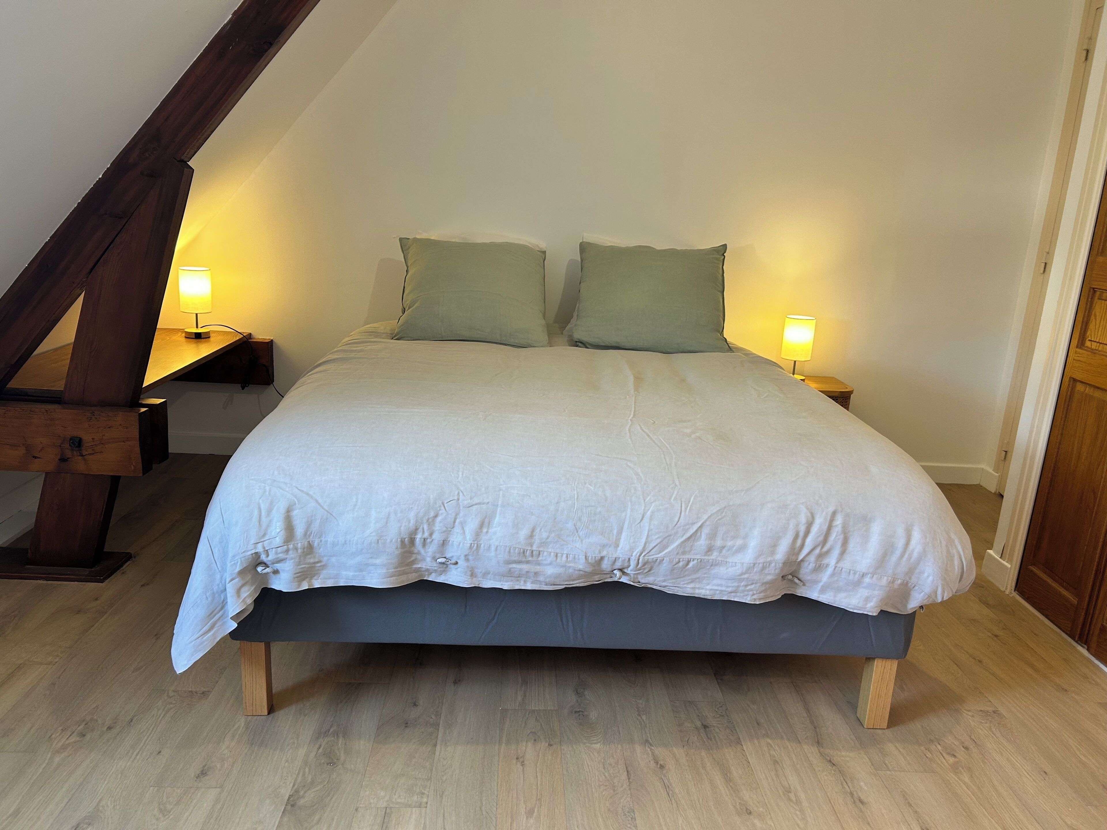Une chambre à coucher avec un lit, deux lampes de chevet et une poutre en bois au plafond.