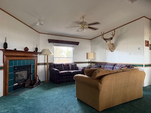 A room with a fireplace, a sofa, a chair, a lamp, a ceiling fan, and a deer head mounted on the wall. - Maria Lake Ranch Retreat #8, located near the  shores of Maria Lake. (Walsenburg)