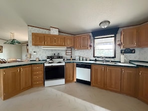 A kitchen with wooden cabinets, a stove, a dishwasher, and a window with blinds. - Maria Lake Ranch Retreat #8, located near the  shores of Maria Lake. (Walsenburg)