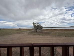 A view of a natural landscape with a tree, open fields, and a body of water under a cloudy sky. - Maria Lake Ranch Retreat #8, located near the  shores of Maria Lake. (Walsenburg)