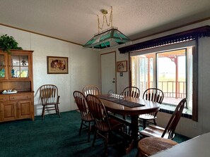 A dining room with a wooden table, chairs, a chandelier, and a view through a window. - Maria Lake Ranch Retreat #8, located near the  shores of Maria Lake. (Walsenburg)