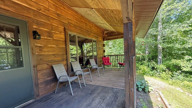 A wooden cabin with a porch, two chairs, and a red chair. - Northwoods Log Cabin on Lake/Pontoon/Kayaks/Screened porch/Fireplace/Fishing/ATV (Hibbing)