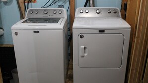 Two white washing machines side by side in a room with wooden flooring and light blue walls. - Northwoods Log Cabin on Lake/Pontoon/Kayaks/Screened porch/Fireplace/Fishing/ATV (Hibbing)