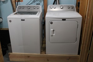 Two white washing machines side by side in a room with wooden flooring and light blue walls.