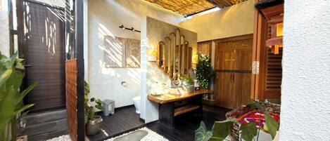 A bathroom with a wooden vanity, a mirror, a sink, and a toilet.