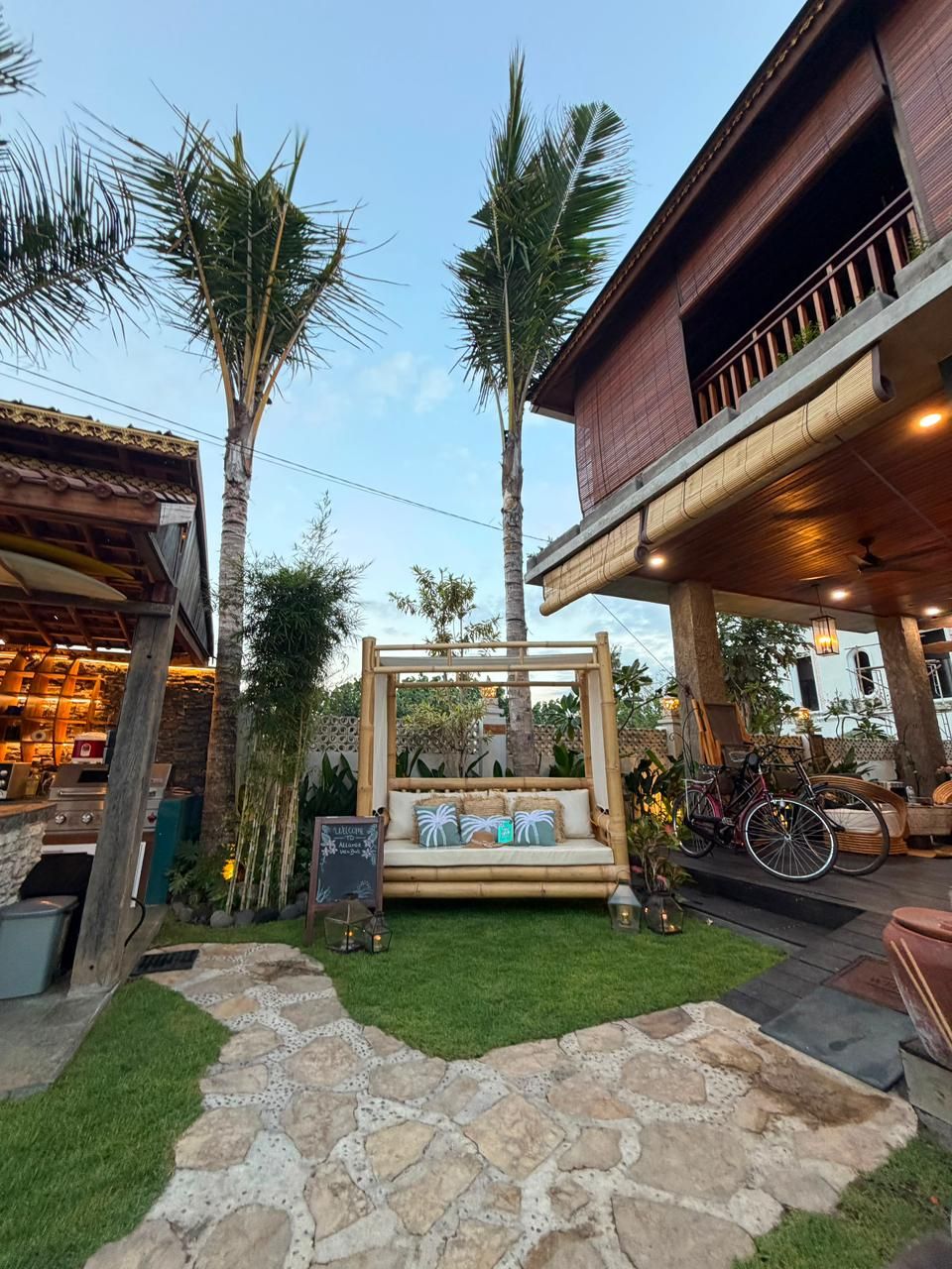 A courtyard with a stone pathway, a wooden bench, and a pergola.