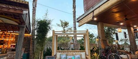 A courtyard with a stone pathway, a wooden bench, and a pergola.