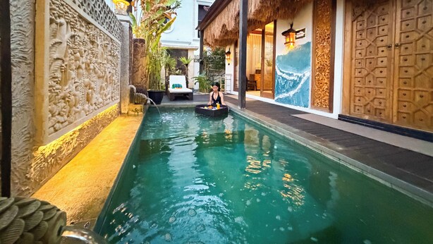 A swimming pool with a person in a boat, surrounded by traditional architecture and decorative elements.
