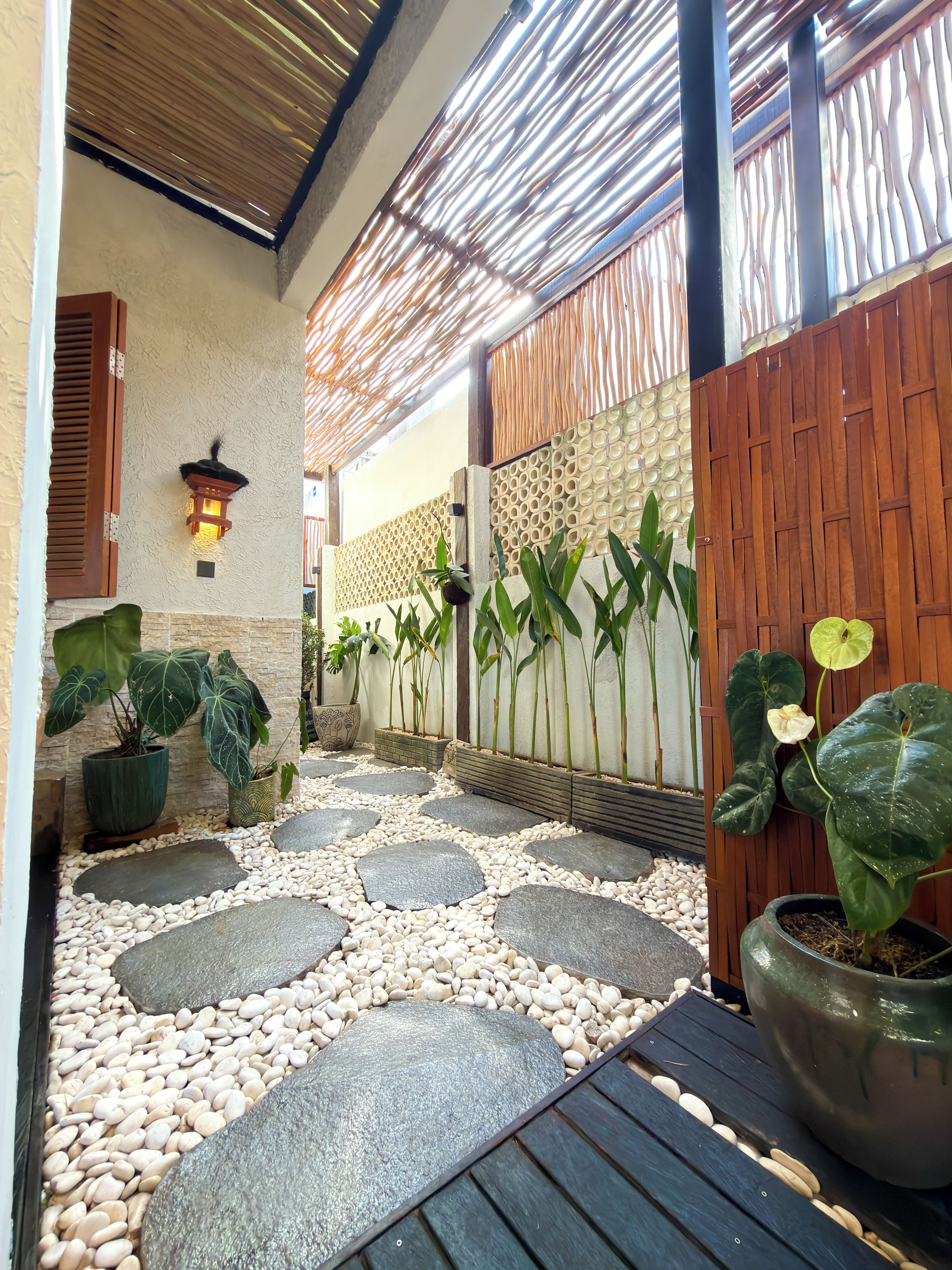 Une cour avec une terrasse en bois, des plantes en pot et un mur décoratif.