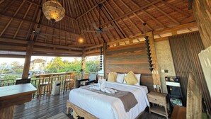 A wooden ceiling with a fan, a bed with pillows, a nightstand, and a water dispenser.